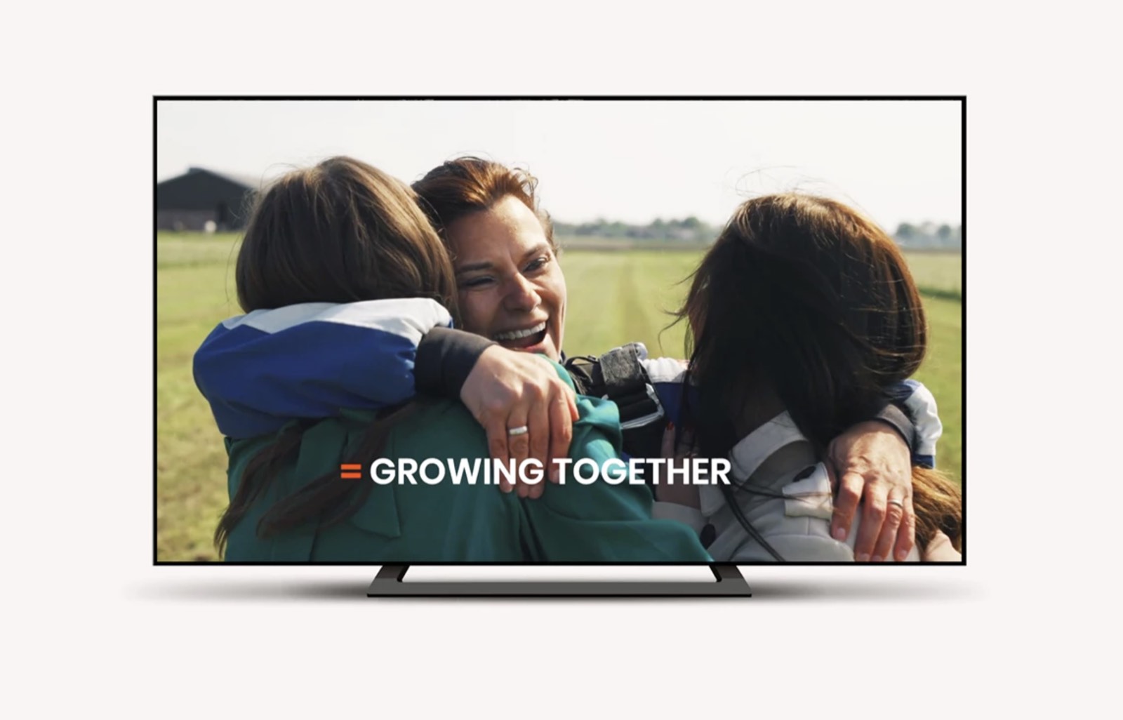 Still uit de Sky High-film: collega's omarmen elkaar in het veld, met de tekst Growing together.